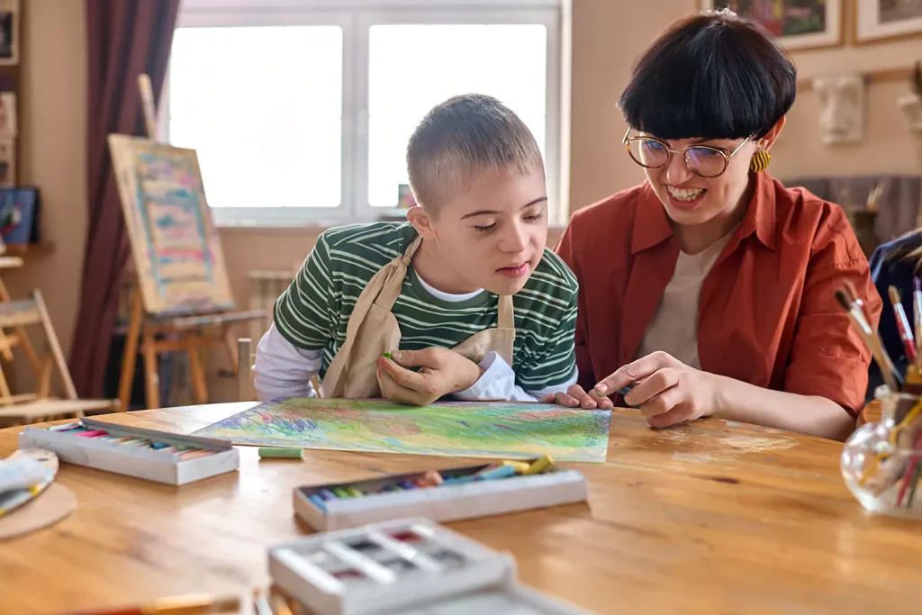 Disabled young man in art class with support worker